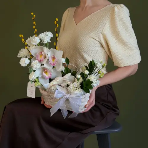 Цветочная композиция из гвоздик, орхидей и вербы с эустомой в плетеной корзине